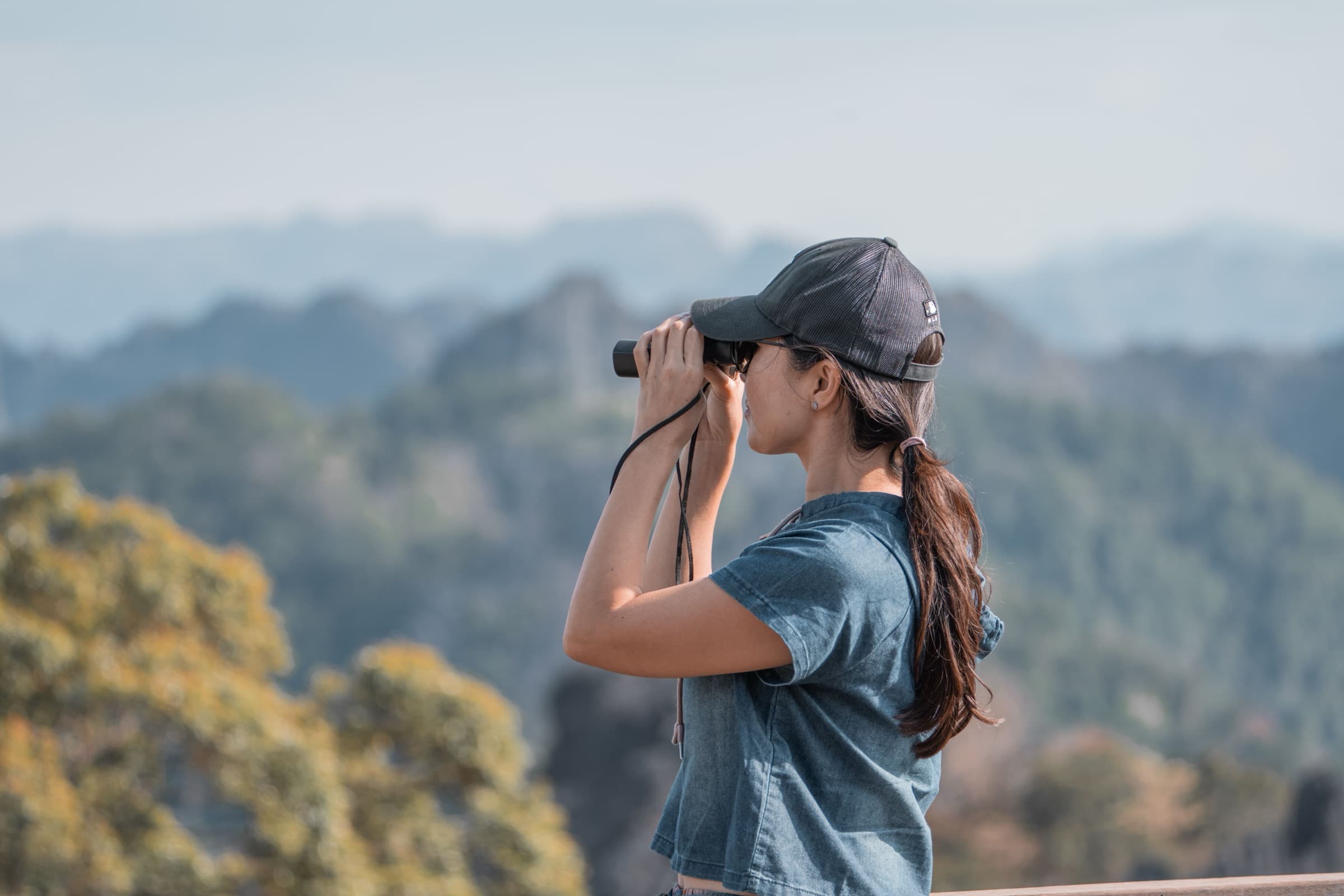 Persoon kijkt met een verrekijker uit over een landschap als beeld voor digitale vindbaarheid en AI-search.